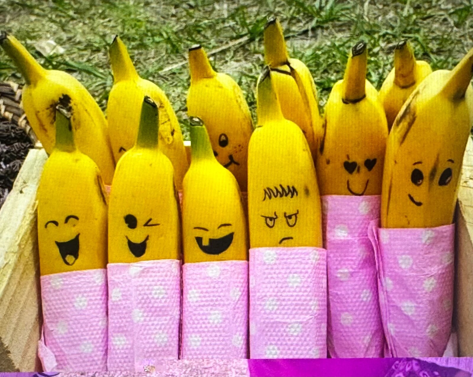 Bananas drawn with expressive faces and wrapped in patterned napkins