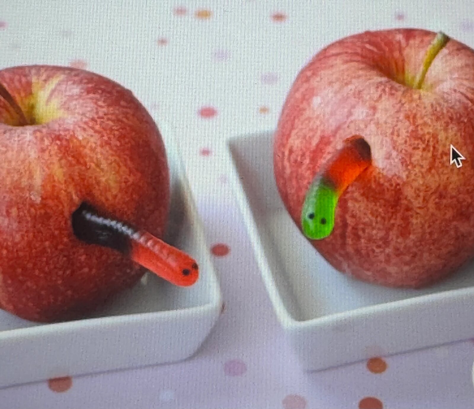 Apples with candy worms emerging, plated on white dishes